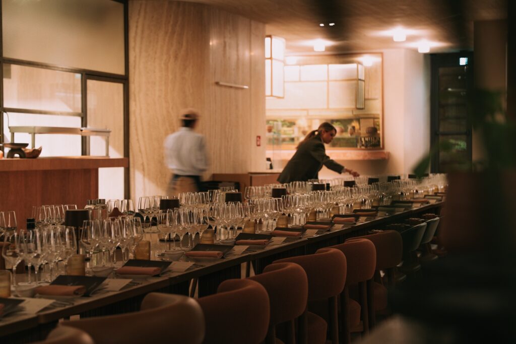 A long fine dining table in Rome, set with crystal glasses for the Cesari Amarone Bosan vertical tasting, featuring clear acrylic chairs and frescoed ceilings.”