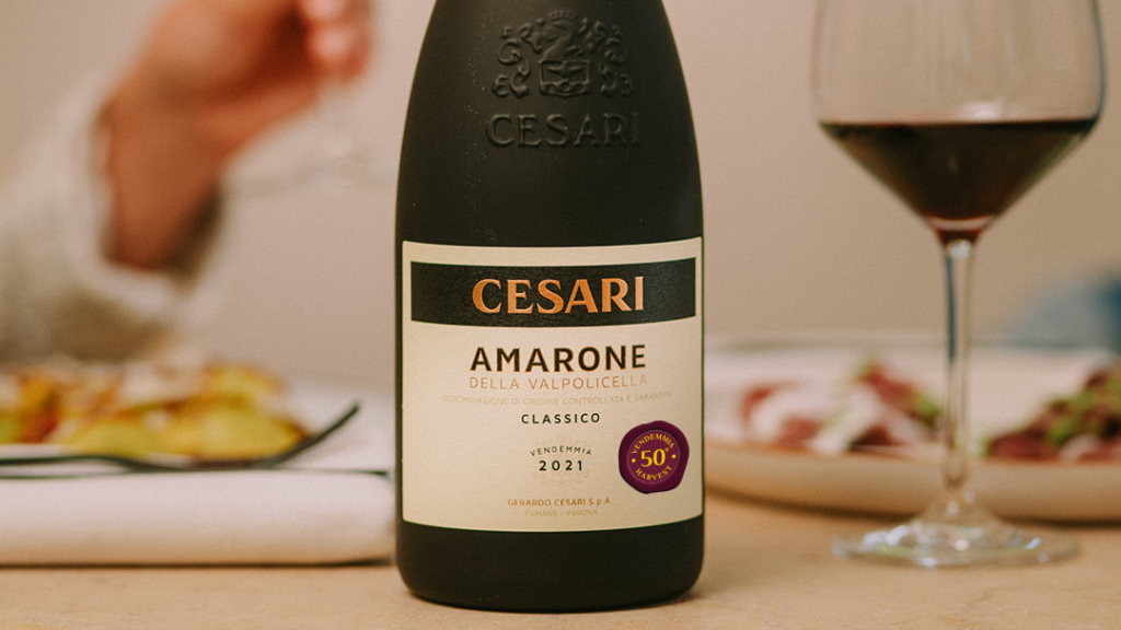 Amarone Classico Cesari 2021_cinquantesimo anniversario_bottle set on a lunch table with two people dining in background