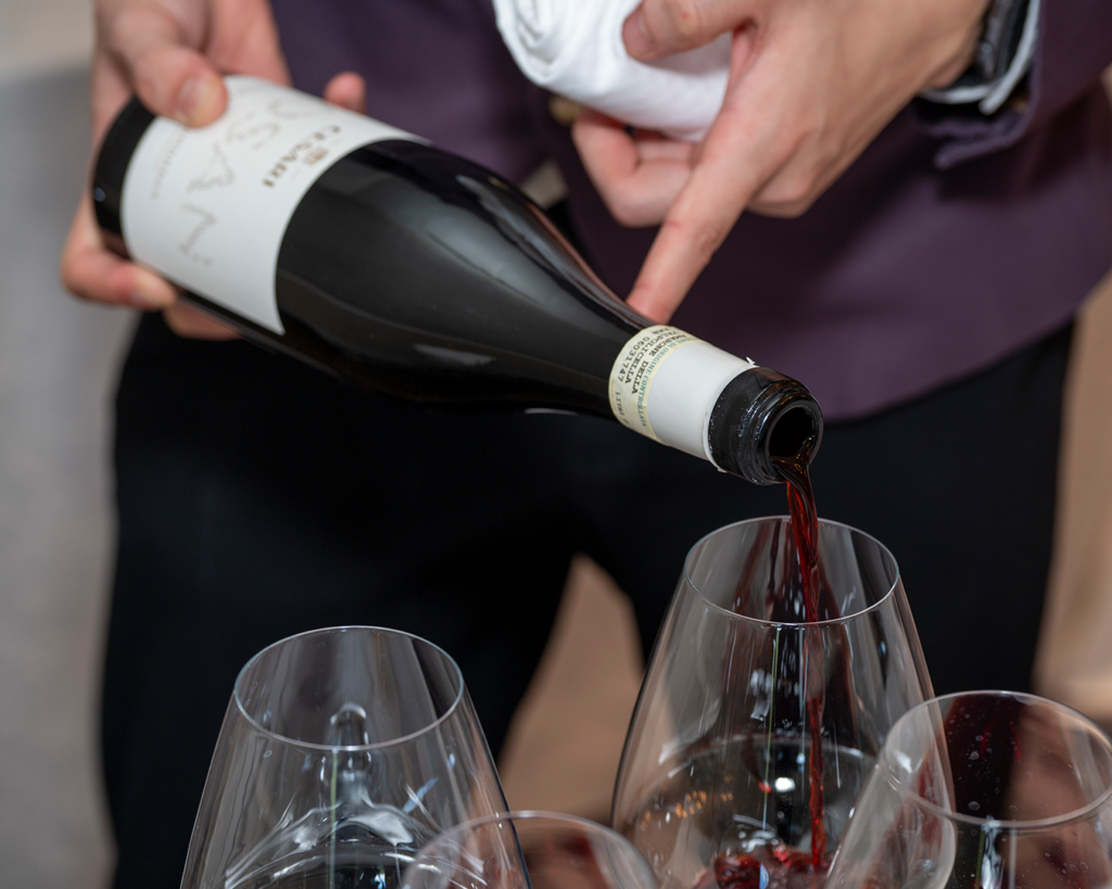 bottle of red wine Bosan Amarone by Cesari being poured into glasses by a waiter
