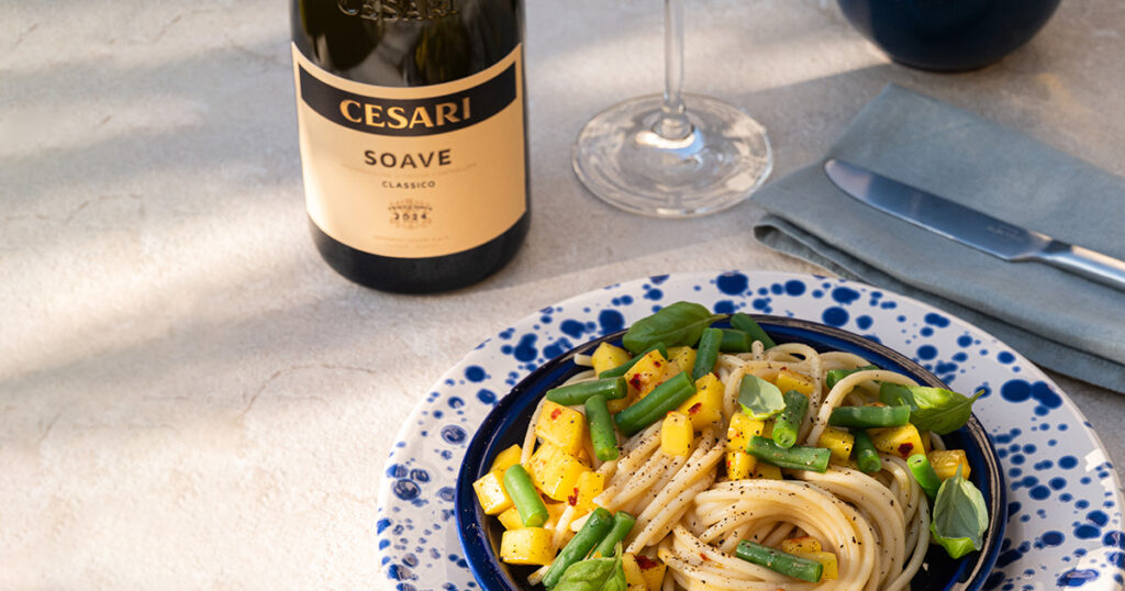 soave classico cesari close-up shot beside a plate of Summer pasta with green vegetables and fish